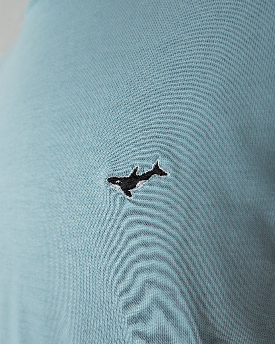 Nahaufnahme des gestickten Orca Motivs auf hellblauem T-Shirt