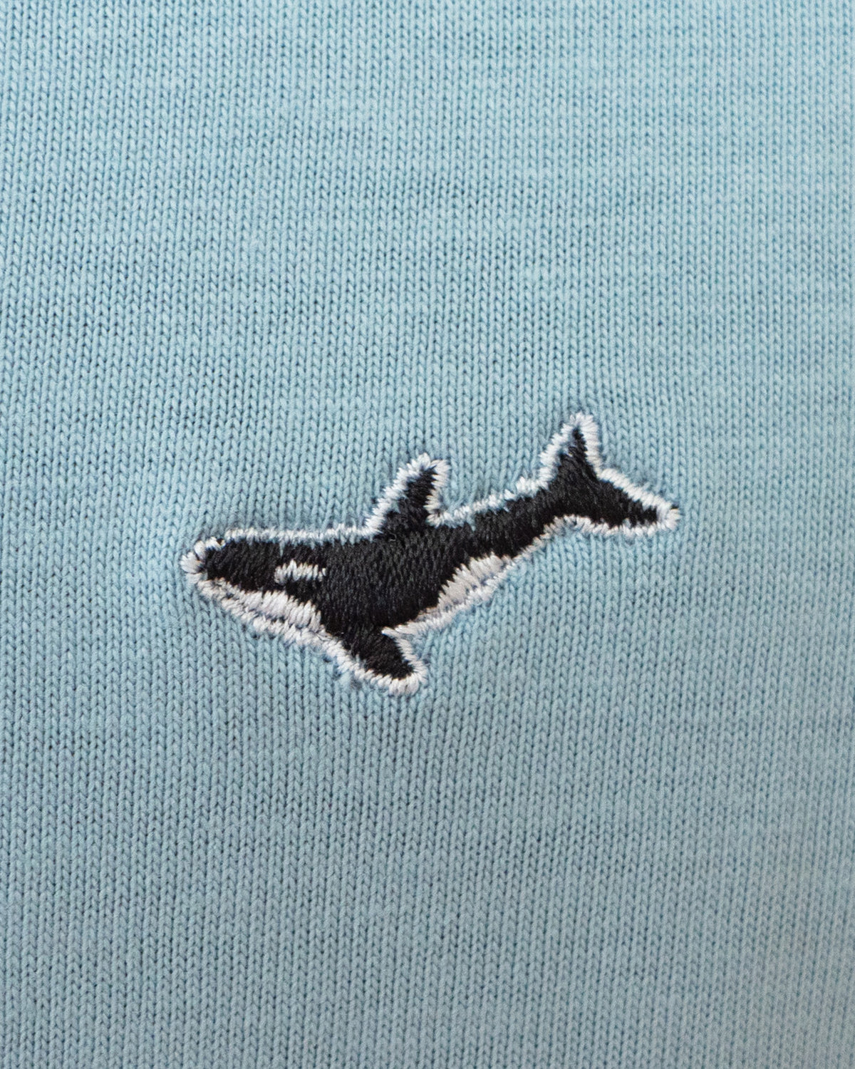 Nahaufnahme des gestickten Orca Motivs auf blauem T-Shirt