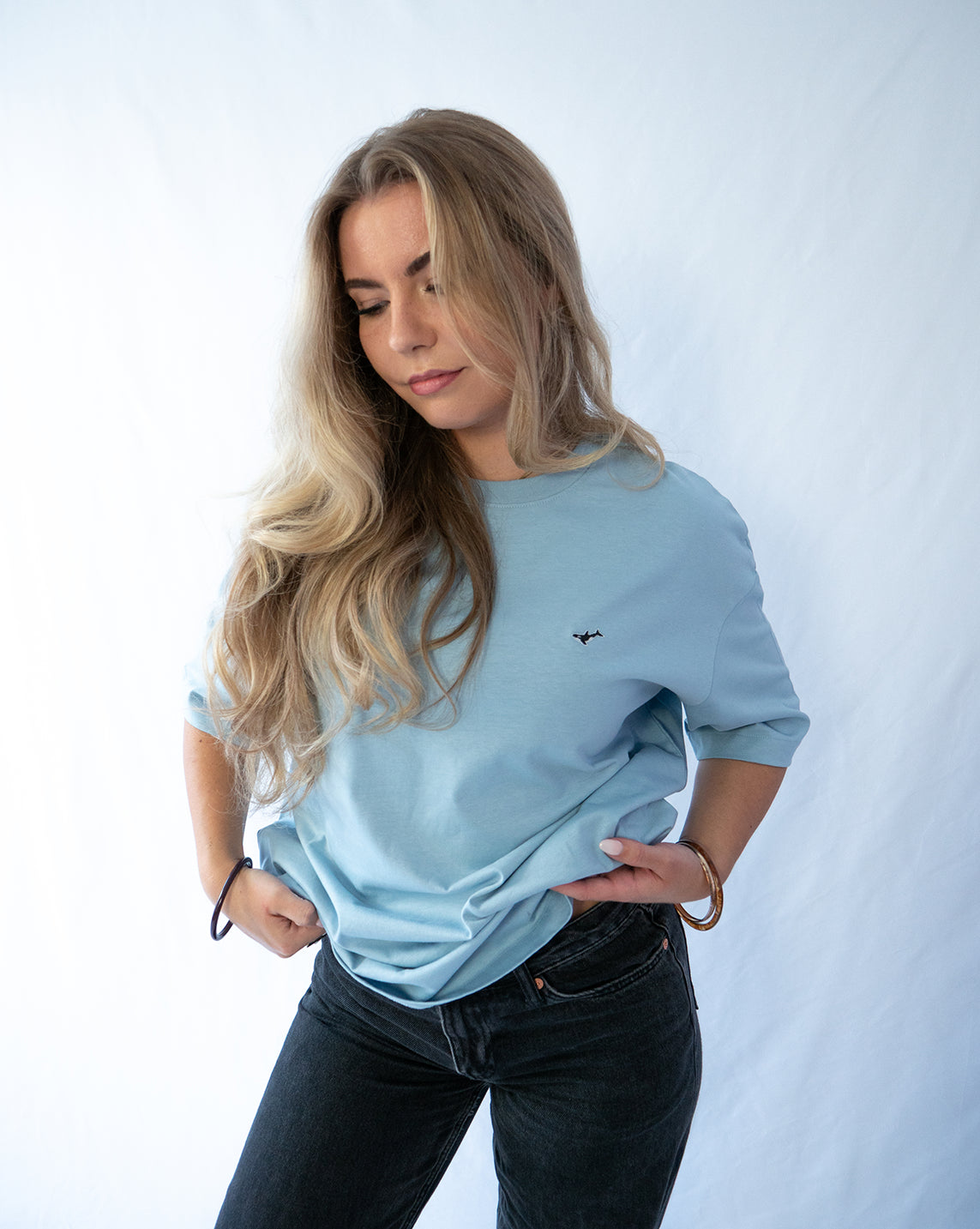 Das Model trägt ein hellblaues oversize Bio-Baumwoll T-Shirt mit gesticktem Orca Motiv auf der Brust