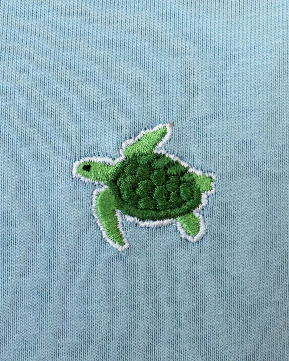 Nahaufnahme des gestickten Schildkröten Motivs auf blauem T-Shirt