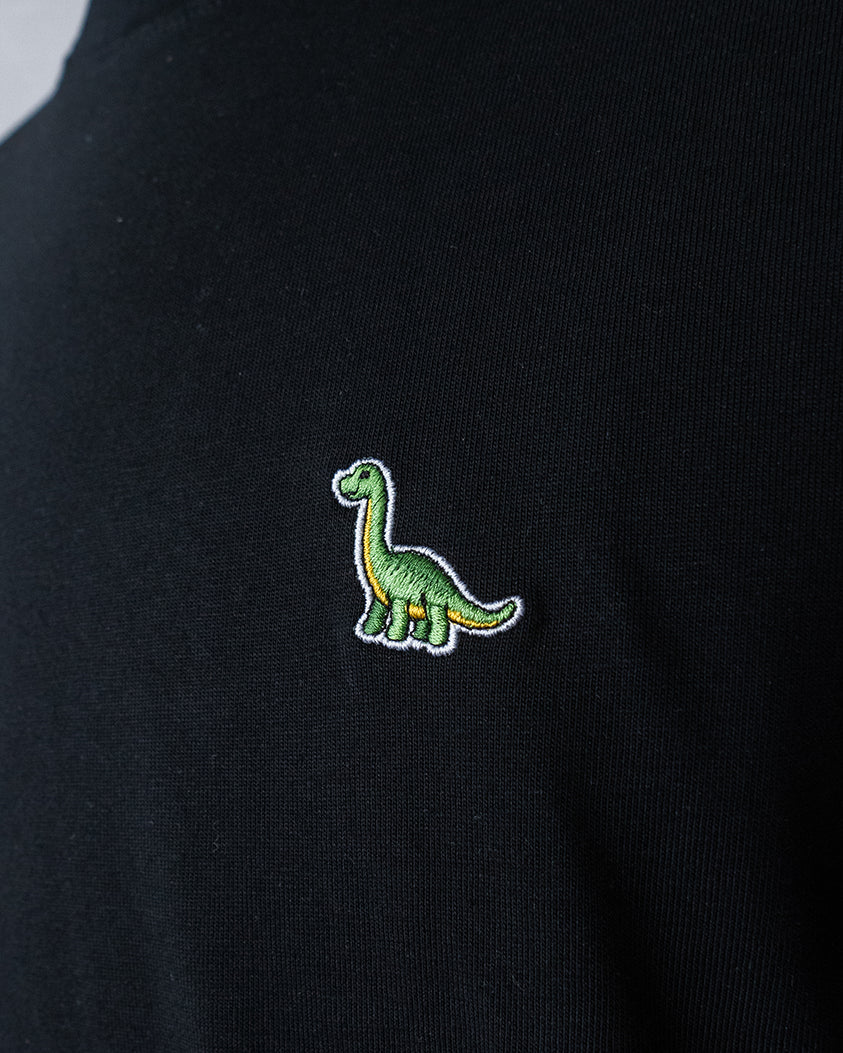 Nahaufnahme des gestickten Brontosaurus Motivs auf schwarzem T-Shirt