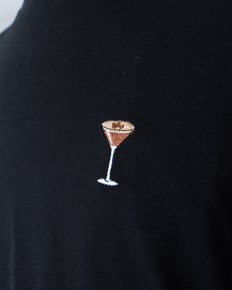 Nahaufnahme des gestickten Espresso Martini Cocktail Motiv auf der Brust auf schwarzem T-Shirt