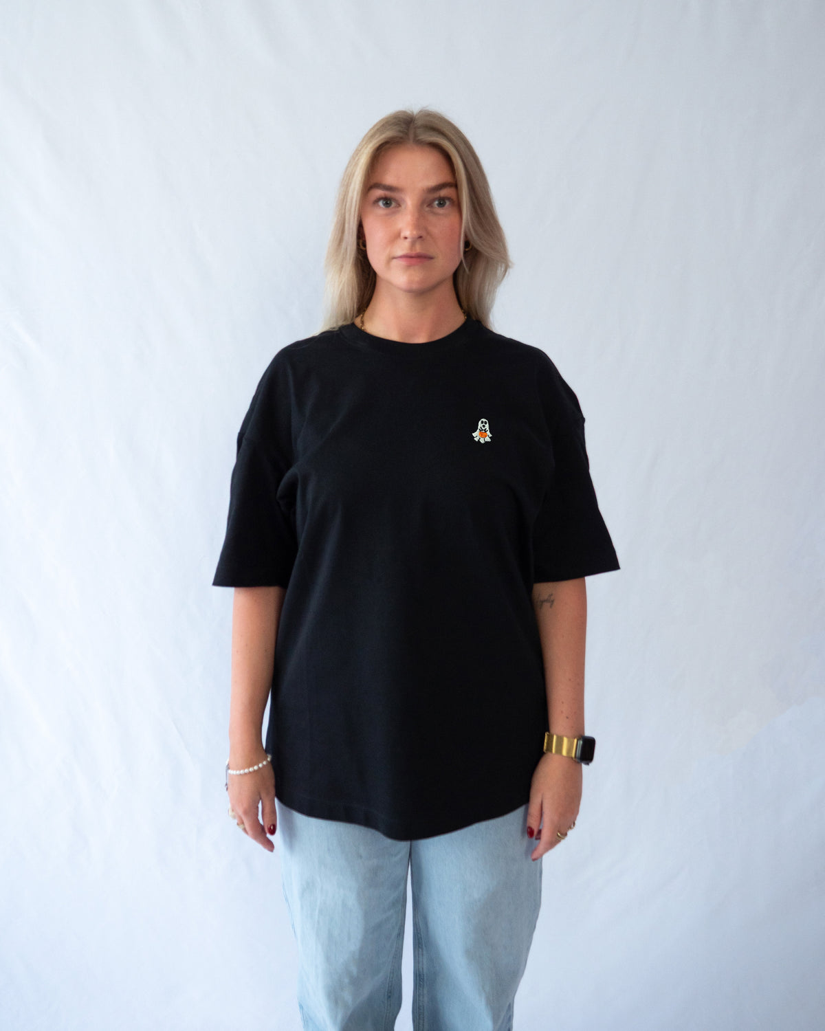 Das Model trägt ein schwarzes Bio-Baumwoll Shirt mit gesticktem Geist mit Kuerbis Motiv