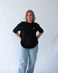 Das Model trägt ein schwarzes Bio-Baumwoll Shirt mit gesticktem Geist mit Kuerbis Motiv