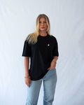Das Model trägt ein schwarzes Bio-Baumwoll Shirt mit gesticktem Geist mit Luftballon Motiv