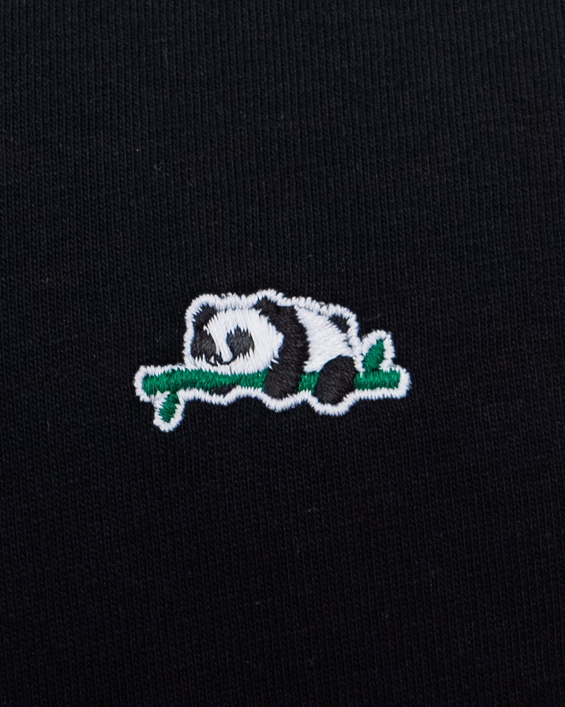 Nahaufnahme des gestickten Panda Motivs auf schwarzem T-Shirt