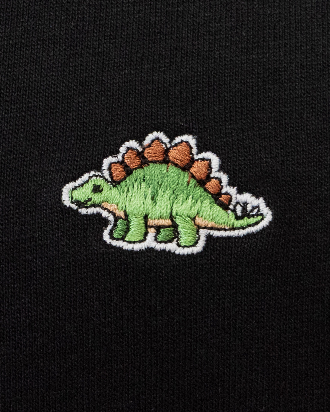 Nahaufnahme des gestickten Stegosaurus Motivs auf schwarzem T-Shirt