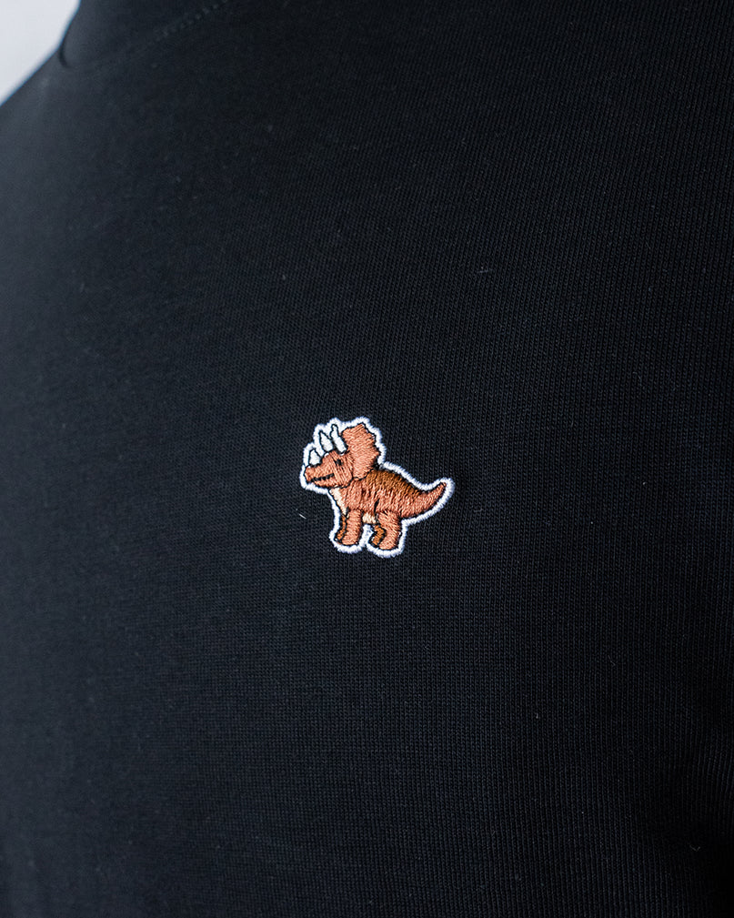 Nahaufnahme des gestickten Triceratops Motiv auf schwarzem T-Shirt