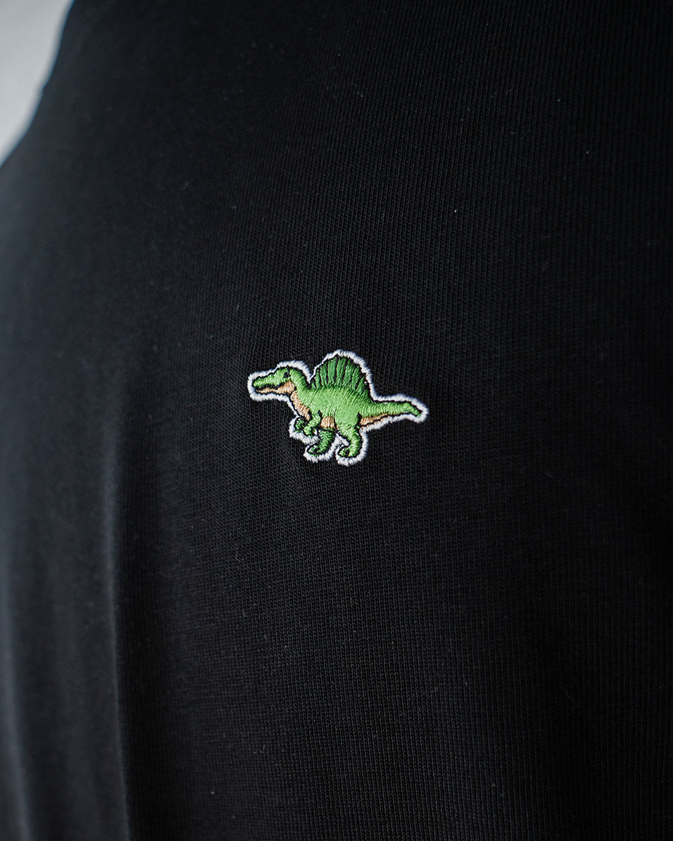 Nahaufnahme des gestickten Spinosaurus Motivs auf schwarzem T-Shirt