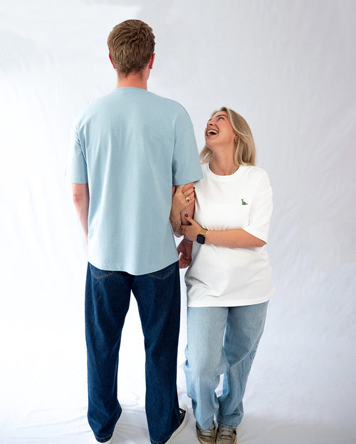 Das Model trägt ein weißes oversize Bio-Baumwoll T-Shirt mit gesticktem Brontosaurus Motiv auf der Brust