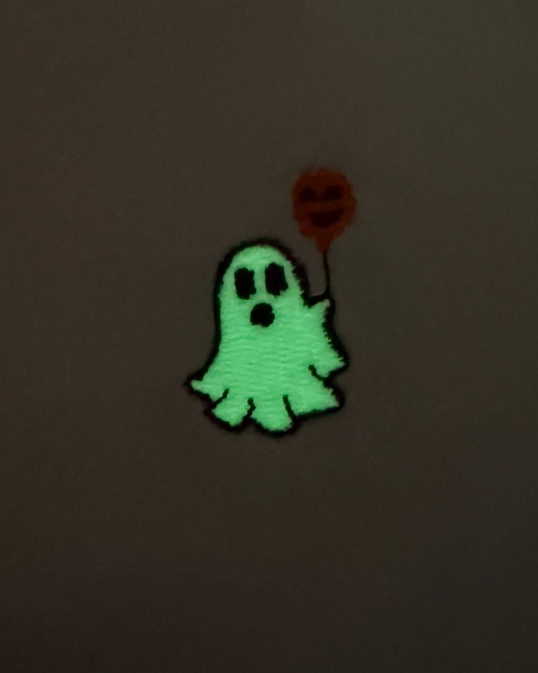 Nahaufnahme des leuchtenden gestickten Geist mit Luftballon Motivs bei Dunkelheit