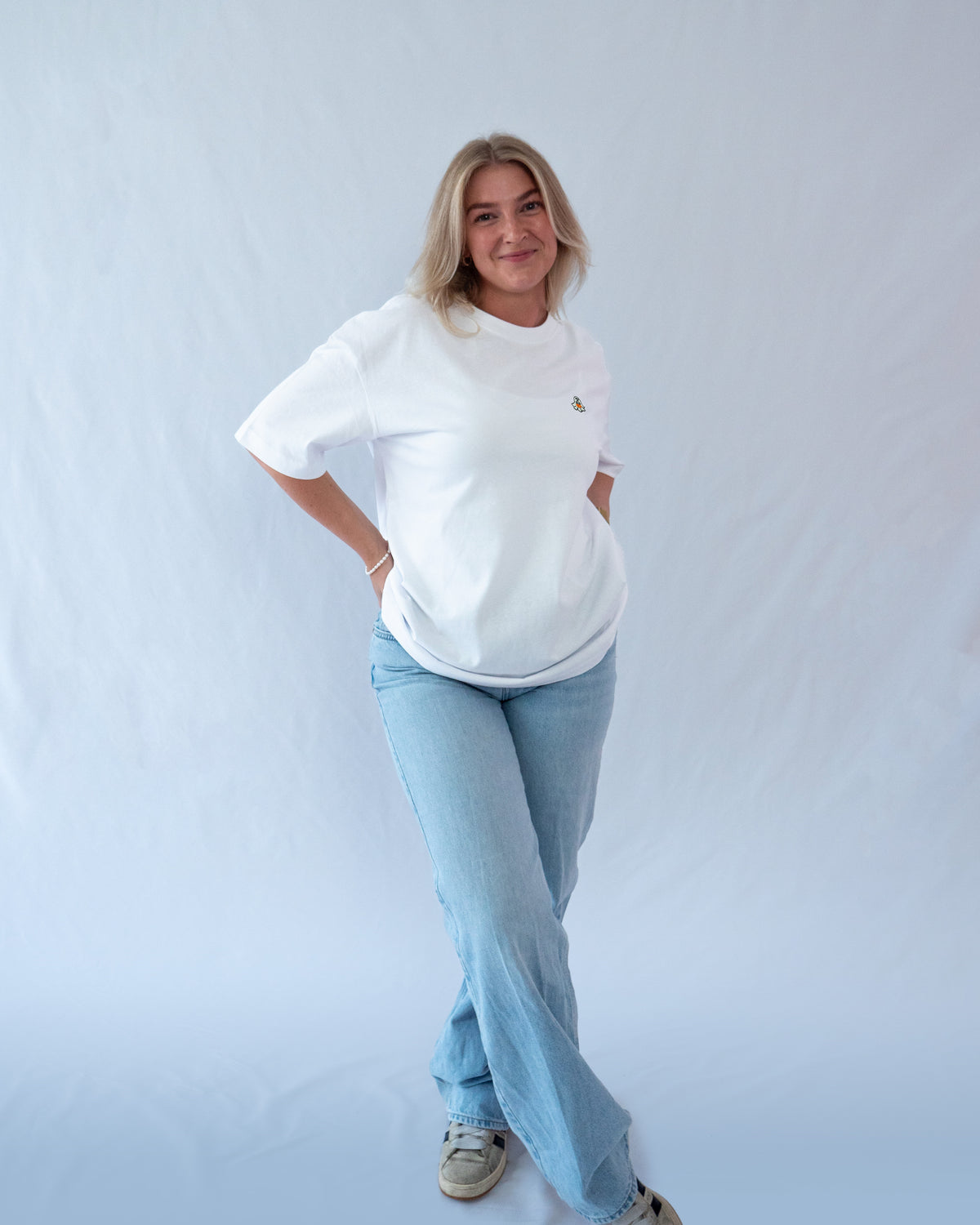 Das Model trägt ein weißes Bio-Baumwoll Shirt mit gesticktem Geist mit Kürbis Motiv