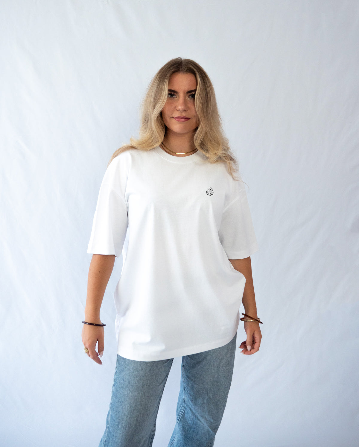 Das Model trägt ein weißes Bio-Baumwoll Shirt mit dezent gesticktem Geist Motiv