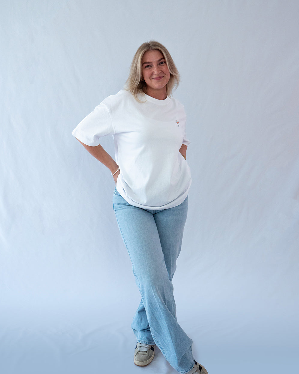 Das Model trägt ein weißes Bio-Baumwoll T-Shirt mit gesticktem Wildberry Cocktail Motiv auf der Brust