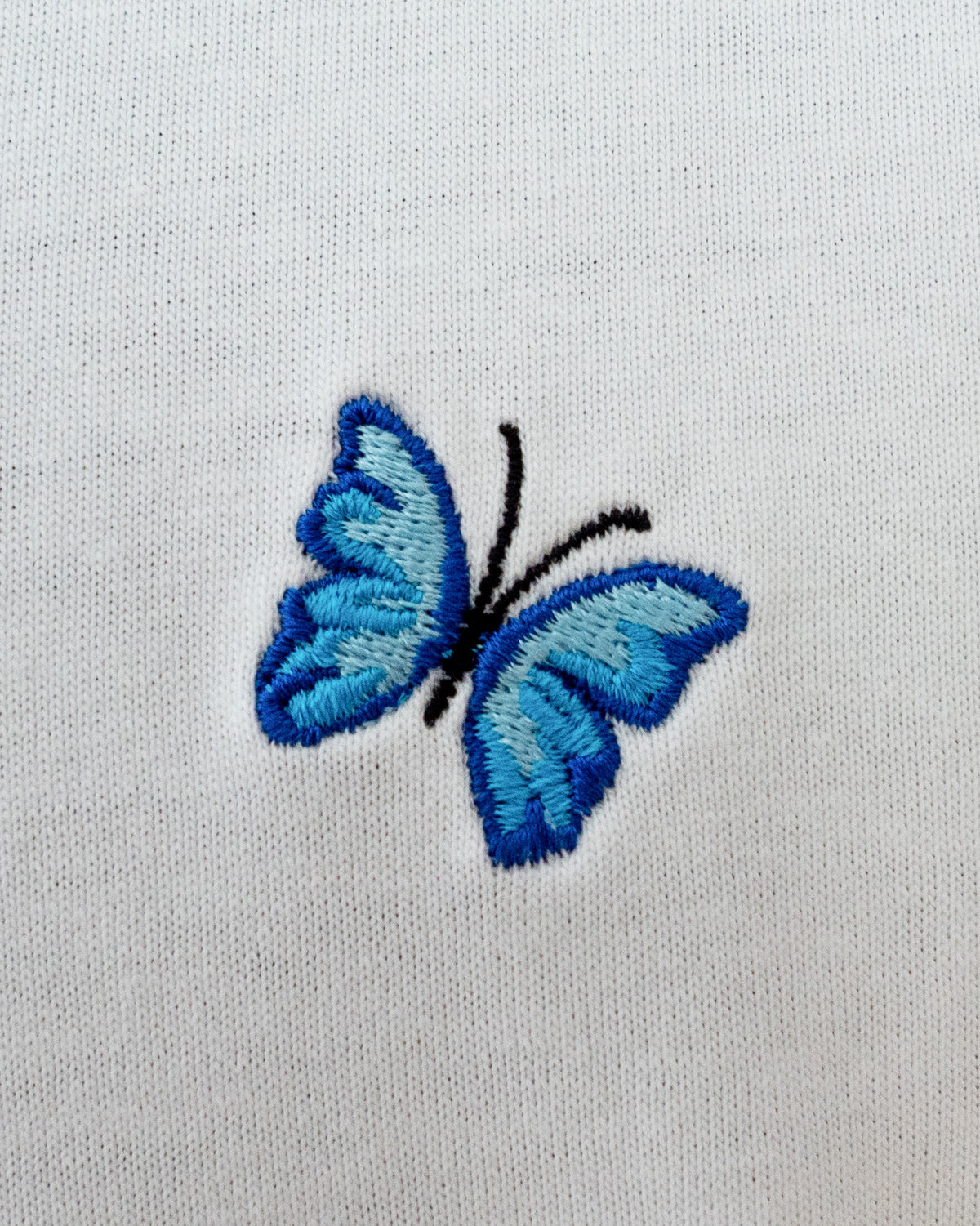 Nahaufnahme des gestickten Schmetterling Motivs auf weißem T-Shirt