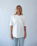 Das Model trägt ein weißes oversize Bio-Baumwoll T-Shirt mit gesticktem Stegosaurus Motiv auf der Brust