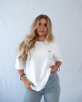 Das Model trägt ein weißes oversize Bio-Baumwoll T-Shirt mit gesticktem T-Rex Motiv auf der Brust